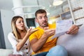 Couple checking bank account trouble sitting on a couch in the living room at home