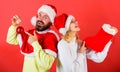 Couple cheerful face check out gift in christmas sock. Christmas gift concept. Woman and bearded man in santa hat Royalty Free Stock Photo