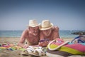 Couple of cheerful senior brothers in holidays at the beach having fun together with smart phone, straw hats and horizon over Royalty Free Stock Photo