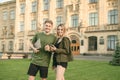 Couple of cheerful students walking after studies, holding laptop and smartphone, smiling, enjoying, laughing, helping each other Royalty Free Stock Photo