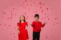 Couple child girl and boy stand in the rain of flying rose petals