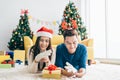 A couple Christmas gift concept. Young happy Asian woman wearing a Santa Claus hat surprised her boyfriend with gloves. Royalty Free Stock Photo