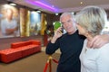 Couple in cinema lobby man on cellphone Royalty Free Stock Photo