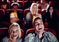 Couple at cinema movie theatre for funny, comic and happy film show in audience auditorium on a date. Smile, relax and