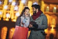 Couple in the city centre with holiday`s brights in background. Couple browsing digital tablet. They are using credit card Royalty Free Stock Photo