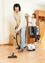 Couple cleaning with vacuum cleaner in home