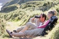 Couple on cliffside outdoors using binoculars Royalty Free Stock Photo