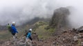 Couple of climbers descending from the Ruminahui volcano by a rock wall on a cloudy day