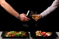 Couple clink glasses on dark background and food on table. dinner concept with man and woman