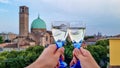 Padua - Couple clinking prosecco glasses with scenic view on Basilica di Santa Maria del Carmine in Padua, Veneto, Italy, Europe