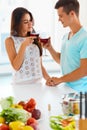 Couple clinking their glasses of red wine in the kitchen Royalty Free Stock Photo