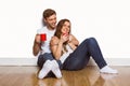 Couple with coffee cups sitting on floor