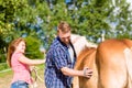 Couple combing horse on pony farm