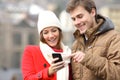 Couple consulting a smart phone in winter