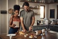 Couple cooking breakfast with a tablet while searching for online recipes and videos on the internet. Happy interracial Royalty Free Stock Photo