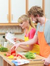 Couple cooking in kitchen reading cookbook Royalty Free Stock Photo