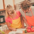 Couple cooking in kitchen reading cookbook Royalty Free Stock Photo