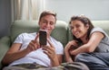 Couple on a couch looking at funny stuff on a mobile phone Royalty Free Stock Photo