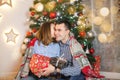 Couple couple in love under a blanket near the Christmas tree give each other gifts Royalty Free Stock Photo