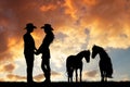 Couple of cowboys with horse at sunset