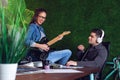 Couple of coworkers enjoying some music in office. Girl playing guitar