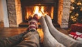 Couple put feet up next to a cozy warm open fire