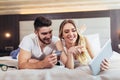 Couple with credit card and digital tablet lying in bed and doing online shopping Royalty Free Stock Photo