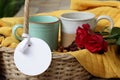 Couple cups of coffee in a basket with blank tag paper label on yellow background. Mugs ceramic with two red roses, rattan basket. Royalty Free Stock Photo