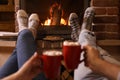 Couple with cups of delicious cocoa resting near fireplace at home. Winter vacation