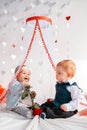 A couple of cute babies posing on a white background decorated with hearts. Vertical. A happy girl holds a rose in her Royalty Free Stock Photo