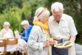 Cute seniors standing close to each other and hlding plate full of food during garden party Royalty Free Stock Photo