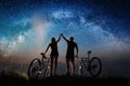 Couple cyclists with mountain bikes at night under starry sky