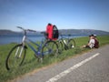 Couple of cyclists are sitting on a meadow