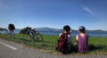 Couple of cyclists are sitting on a meadow