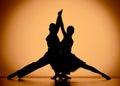 Couple of dancers are dancing elements of Argentine tango. Black silhouettes of man and woman on an orange brown Royalty Free Stock Photo