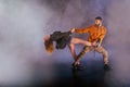 Couple dancing modern dance and showing off their leg stretch moves.Black background while the couple is dressed in urban colorful Royalty Free Stock Photo