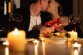 Couple dating for Valentine's day, dinner for two with wine and candles, romance and kiss of lovers, holding gift with Royalty Free Stock Photo