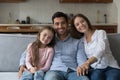 Couple and daughter smile look at camera seated on sofa Royalty Free Stock Photo