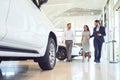 Couple and the dealer selling cars look the car in the showroom. Royalty Free Stock Photo