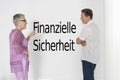 Couple discussing financial security against white wall with German text Finanzielle Sicherheit