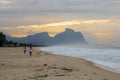 Couple and dog running on the beach of Barra da Tijuca in a beautiful dawn with the stone of Gavea in the background - Rio de Jane Royalty Free Stock Photo