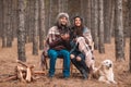 Couple with a dog is sitting in the forest, drinking tea , and watching to the distance. Outdoors. Royalty Free Stock Photo