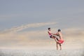 Young sporty couple practicing acroyoga exercises at sunrise or sunset.