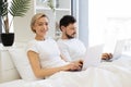 Couple doing distant work on laptops in bed