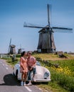 couple doing a road trip with an old vintage sport car by the Dutch windmill village Schermerhorn Royalty Free Stock Photo