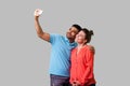 Couple doing selfie! Portrait of positive young man and woman in casual wear taking pictures. isolated on gray background, indoor Royalty Free Stock Photo