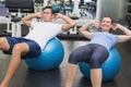 Couple doing sit ups on exercise balls Royalty Free Stock Photo