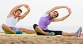 Couple doing yoga poses sitting on sunny beach by sea Royalty Free Stock Photo