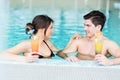 Couple drinking a cocktail by the swimming pool