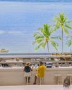 Couple drinking cocktails in the bar looking out over a blue ocean with palm trees Royalty Free Stock Photo